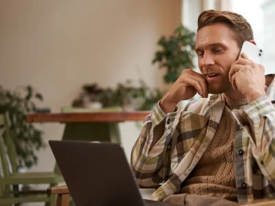 Mlad moški, ki gleda v računalnik in govori po telefonu