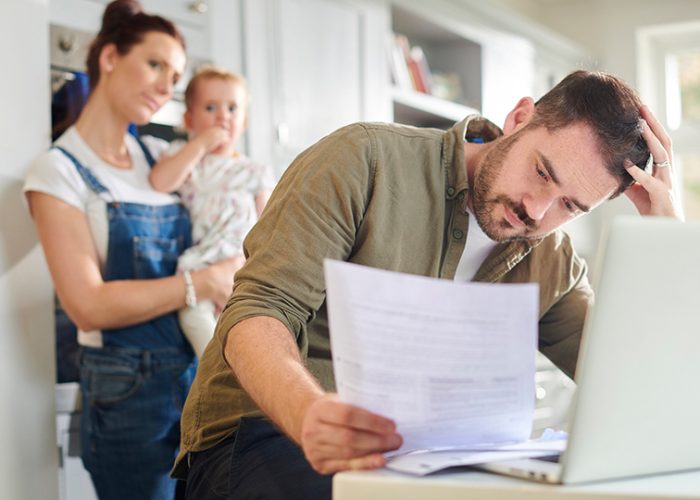 Blog-hero_managing-personal-finances-during-a-crisis_Man-sitting-at-kitchen-table-reviewing-bills-while-family-looks-on_1015x540